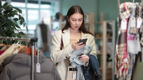 Young woman scans qr code of jeans in store Stock Footage 329399269