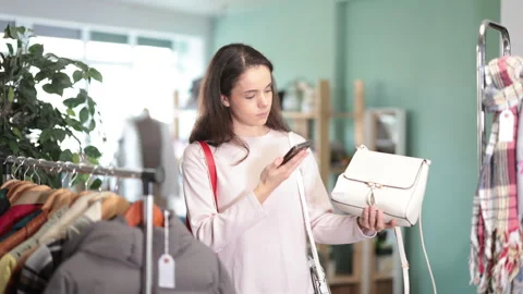 Young woman scans qr code of handbag in store Video stock 335618898