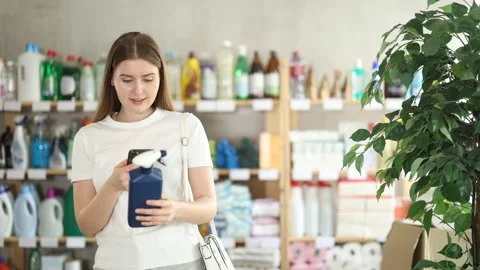 Young woman scans the spray barcode on her mobile and reads detailed Stock Footage 341531374