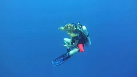 Young woman scuba diver hangs in blue water at the safety stop Stock Footage