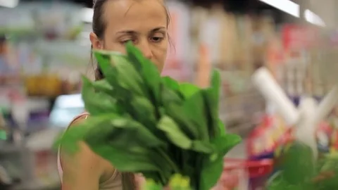 Young woman with selecting greens at supermarket Stock Footage