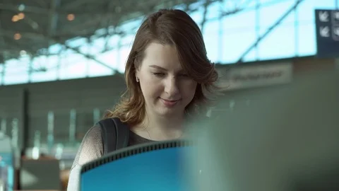 Young woman at self service transfer area doing self-check-in at automated Stock Footage