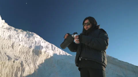 Young woman serving and drinking mate beside a white salt mountain in Salinas Stock Footage 324791882