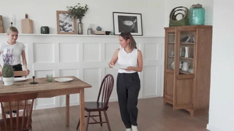 A young woman sets the table for dinner. Woman setting table in stylish kitchen Stock Footage 131864285