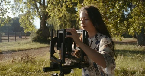 Young woman setting up large format camera in nature Stock Footage 117581830