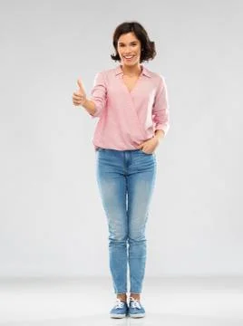 Young woman in shirt and jeans showing thumbs up Stock Photos