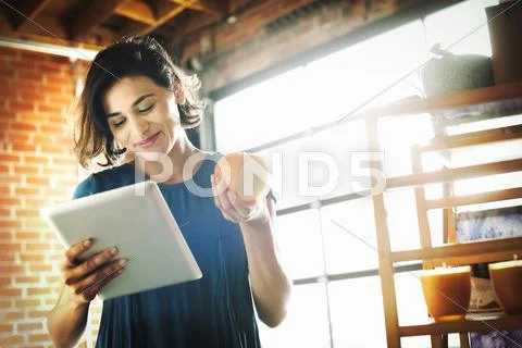Young woman in a shop, holding a digital tablet and a scented candle. Stock Photos