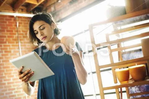 Young woman in a shop, holding a digital tablet and a scented candle. Stock Photos