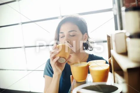 Young woman in a shop, smelling a scented candle. Stock Photos