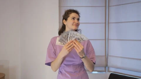 Young woman shows off a stack of United States currency inside her apartment Stock Footage 324911413