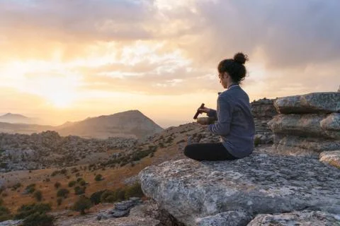 Young woman with singing bowl meditating in mountains Stock Photos