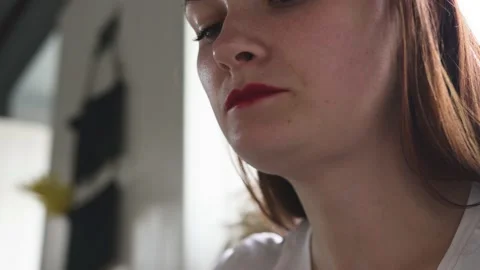 A young woman sits in a cafe, eats food, chews, licks her lips, swallows food Stock Footage 137565531