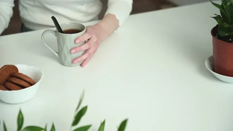 Young woman sits down at table to drink coffee with cookies Stock Footage 169430601