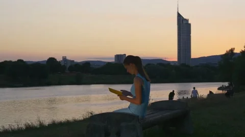 Young woman sits with e-reader near the river Video stock 66429540