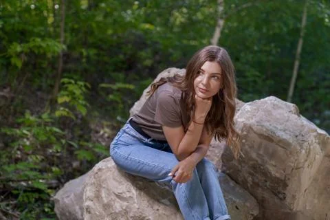 Young woman sits on stones in a forest Stock Photos