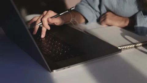 A young woman sits at a table and works on a laptop online from home Stock Footage