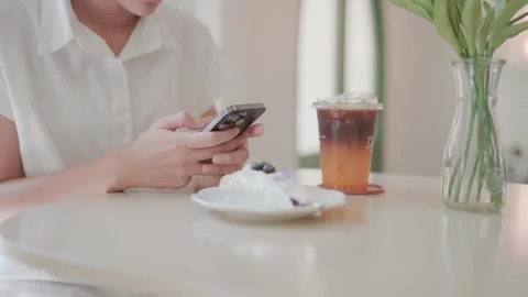 .A young woman sits while borrowing coffee and typing messages while surfing the Video stock 262220834