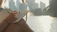 Young Woman Sitting On The Bench In Park And Writing In Diary, Close-Up Stock Footage