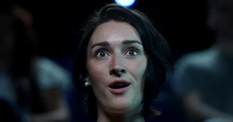 A young woman sitting in a cinema reacting to something incredible on screen Stock Footage