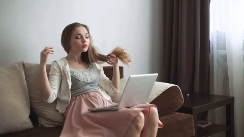 Young woman sitting on couch using laptop and smiling Stock Footage 74434526