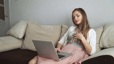 Young woman sitting on couch using laptop and smiling Stock Footage 74435658