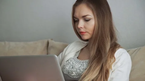 Young woman sitting on couch using laptop and smiling Stock Footage 74435922