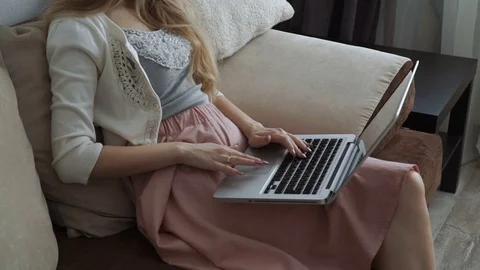 Young woman sitting on couch using laptop and smiling Stock Footage 74443963