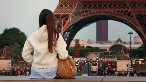 Young woman sitting in front of the Eiffel Tower. Video stock 252036857