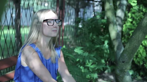 Young woman sitting outside contemplating, looking into camera Stock Footage 59143273