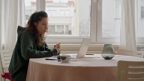 Young woman sitting at table with computer talking in conference call at home Stock Footage 218463992