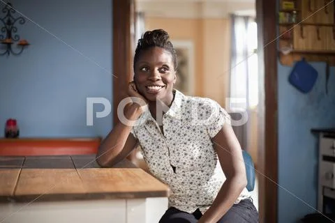 A young woman sitting at a table in a domestic kitchen Stock Photos