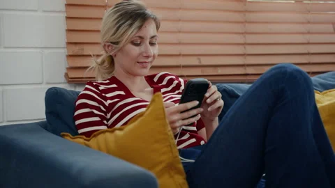 Young woman sitting using mobile phone in living room Stock Footage 239557595