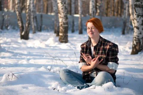 Young woman sitting in winter forest. Stock Photos