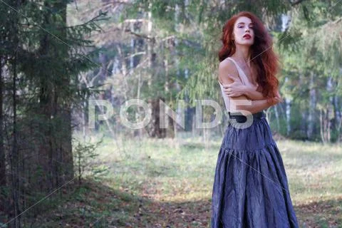 Young woman in skirt and belt poses on wind in sunny autumn forest Stock Photos
