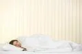The young woman sleeping on the bed on the background of a blind Photo