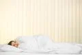 The young woman sleeping on the bed on the background of a blind Photo