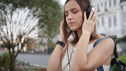 Young woman with smartphone and headphones listening to music on city street. Stock Footage