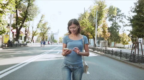 Young woman with smartphone walking in the city, steadicam shot Stock Footage
