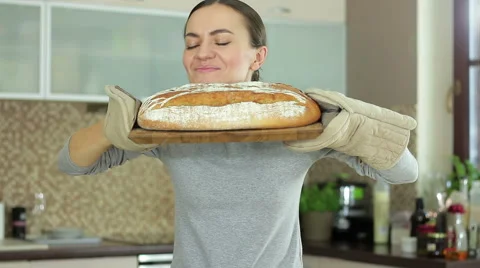 Young woman smelling freshly baked bread in kitchen HD 스톡 동영상 59123124