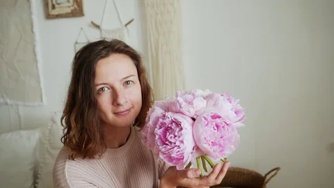 Young woman smells pink rose and smiles Stock Footage