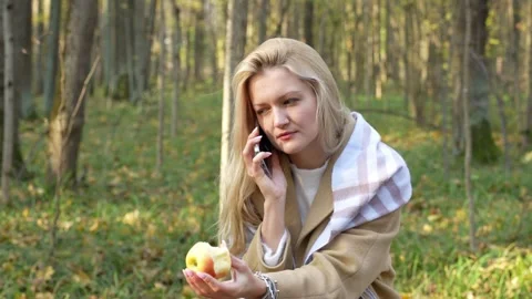 Young woman smiles while talking on the phone in the middle of an autumn park Stock Footage 287933017