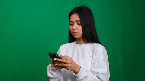 Young woman smiles while using her smartphone to browse, text, and chat Stock Footage 276081224