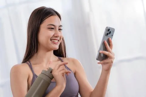 Young woman smiles while using smartphone in a bright room during daytime Stock Photos