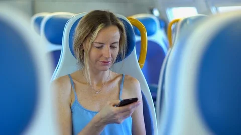 Young woman smiling and using smartphone in the train. Technology and internet c Stock Footage 80253194