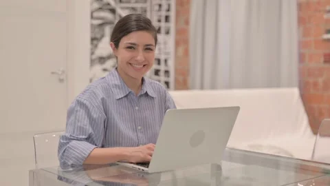 Young Woman Smiling at Camera while Working on Laptop Stock Footage 238647740