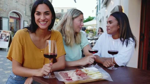 Young woman smiling at camera while drinking red wine with friends at restaurant Stock Footage 302842221