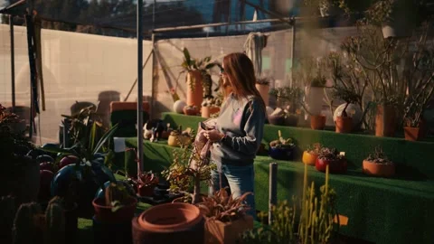 Young woman smiling at cat in cactus nursery - cinematic lifestyle Stock Footage 335241753