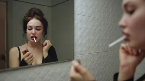 Young woman smiling with cigarette while preparing to light it in front of mirro Stock Footage 314905485
