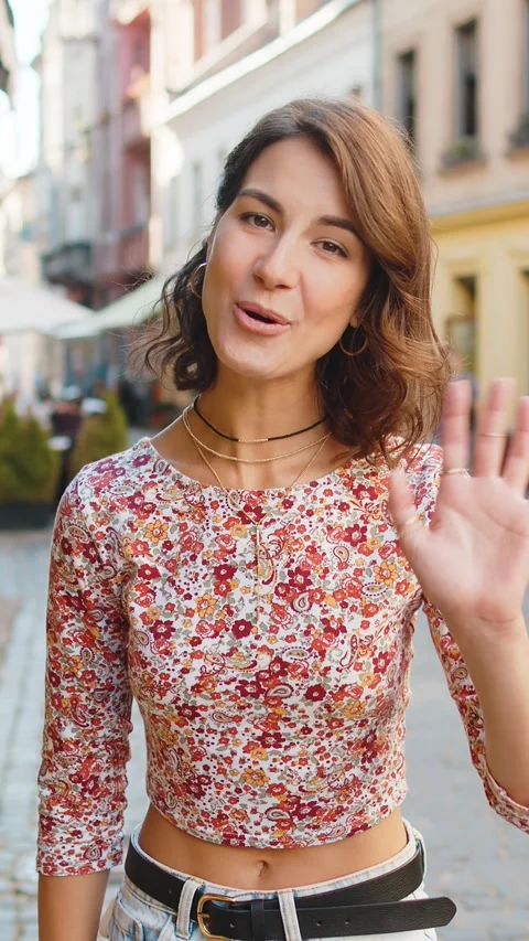 Young woman smiling friendly at camera, waving hands hello, hi, greeting or Stock Footage 323363687