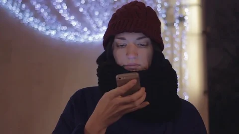 Young woman smiling using a smartphone. City at night. Festive lighting Stock Footage 83079402